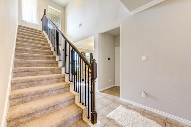 staircase featuring tile patterned floors and crown molding