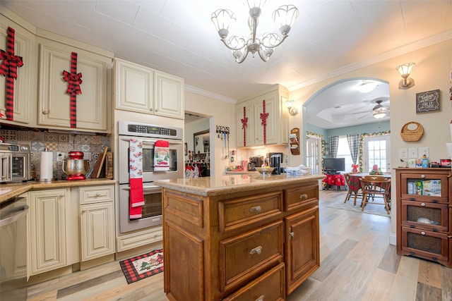 kitchen featuring hanging light fixtures, cream cabinetry, stainless steel appliances, and light hardwood / wood-style flooring