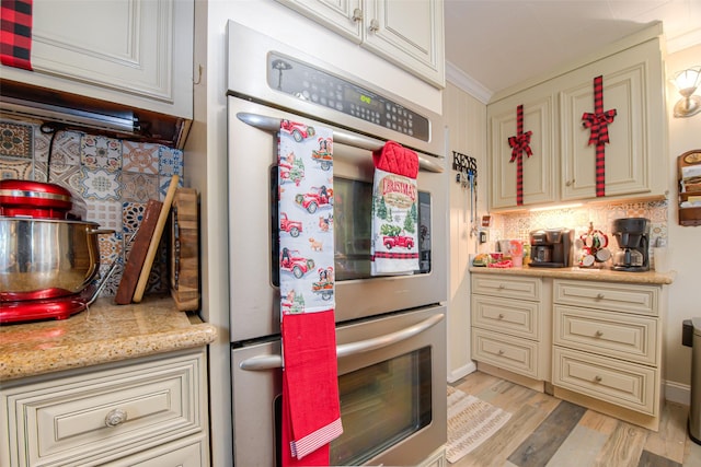 kitchen with backsplash, cream cabinets, refrigerator, crown molding, and light hardwood / wood-style floors