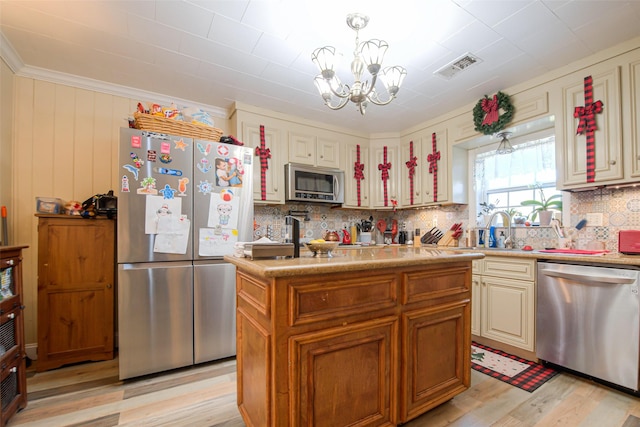 kitchen featuring light wood-type flooring, stainless steel appliances, decorative light fixtures, an inviting chandelier, and a kitchen island