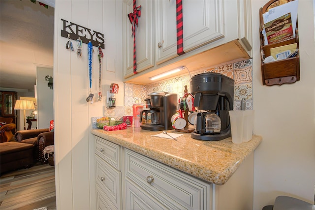 kitchen featuring light wood-type flooring, light stone countertops, and tasteful backsplash