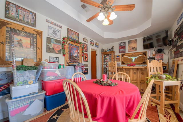 dining space with a raised ceiling and ceiling fan