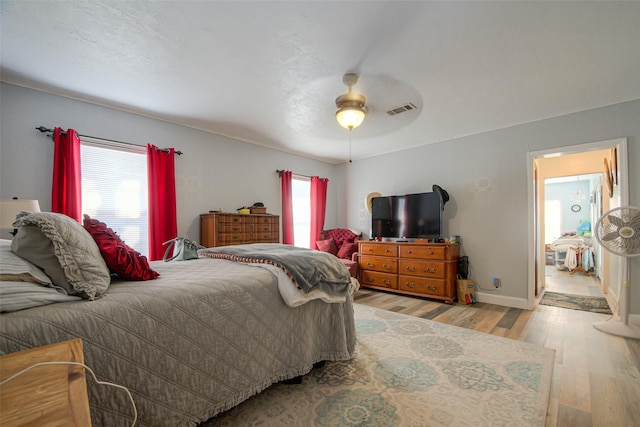 bedroom with multiple windows, ceiling fan, and light wood-type flooring