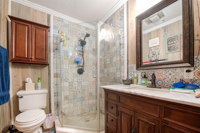 bathroom featuring a textured ceiling, toilet, a shower with door, vanity, and ornamental molding