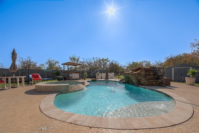 view of pool featuring an in ground hot tub, pool water feature, a patio area, and a storage shed