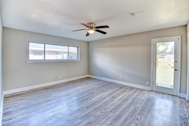 empty room featuring a textured ceiling, light hardwood / wood-style floors, and ceiling fan