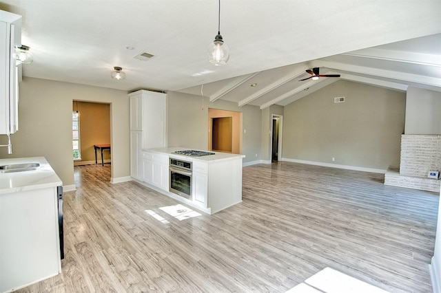 kitchen with pendant lighting, white cabinets, lofted ceiling with beams, appliances with stainless steel finishes, and light hardwood / wood-style floors