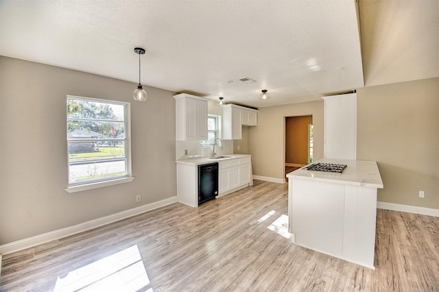 kitchen with white cabinets, sink, black dishwasher, decorative light fixtures, and stainless steel gas cooktop