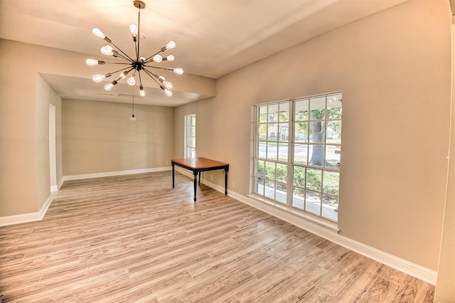 empty room with a chandelier and light wood-type flooring