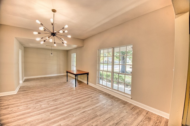 empty room featuring light hardwood / wood-style floors and a chandelier