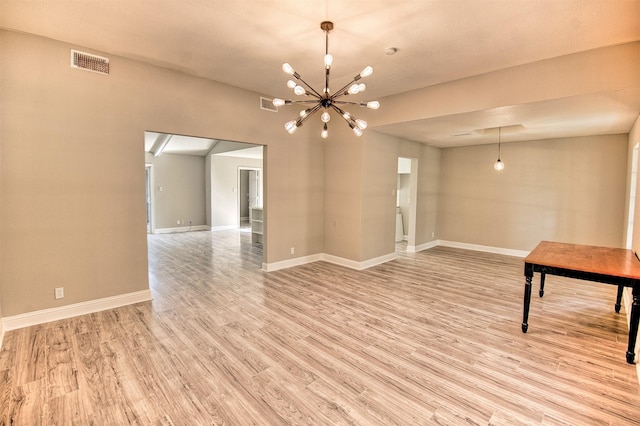 empty room with light hardwood / wood-style floors and a chandelier