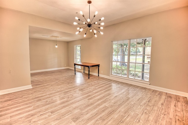 empty room featuring light hardwood / wood-style flooring and a chandelier