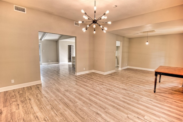 spare room featuring light hardwood / wood-style floors and a notable chandelier