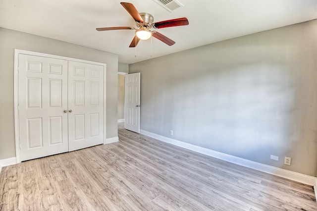 unfurnished bedroom featuring ceiling fan, a closet, and light wood-type flooring