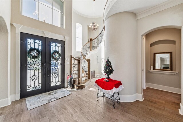 foyer featuring french doors, crown molding, hardwood / wood-style flooring, and a notable chandelier