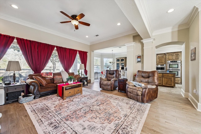 living room with ornate columns, ceiling fan, light wood-type flooring, and crown molding