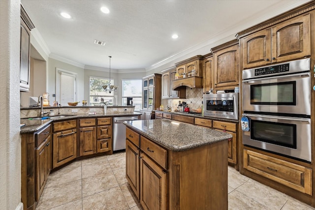 kitchen featuring sink, hanging light fixtures, stainless steel appliances, a center island, and kitchen peninsula