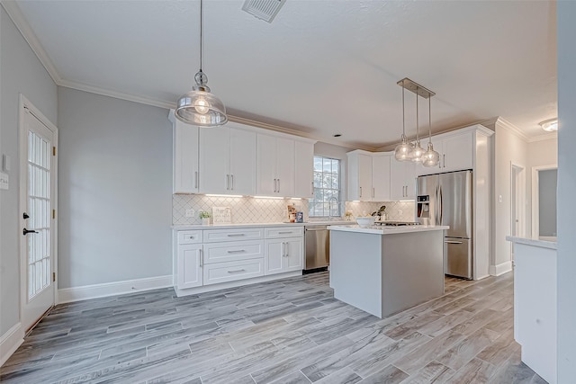 kitchen with a center island, appliances with stainless steel finishes, white cabinetry, and pendant lighting