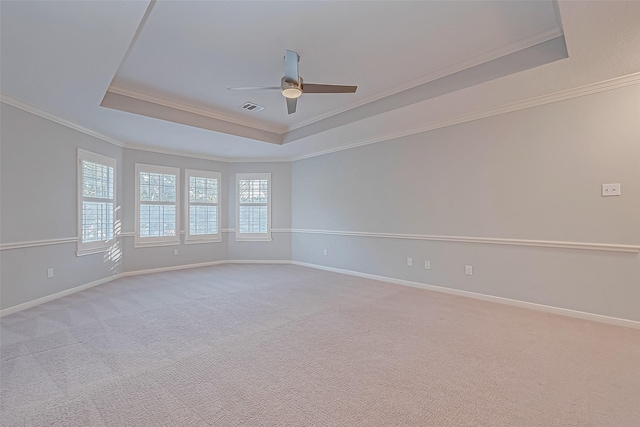 unfurnished room with a raised ceiling, light colored carpet, ceiling fan, and crown molding