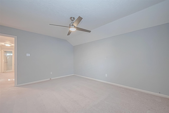 unfurnished room featuring vaulted ceiling, ceiling fan, a textured ceiling, and light carpet