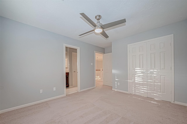 unfurnished bedroom with ceiling fan, light colored carpet, a closet, and a textured ceiling