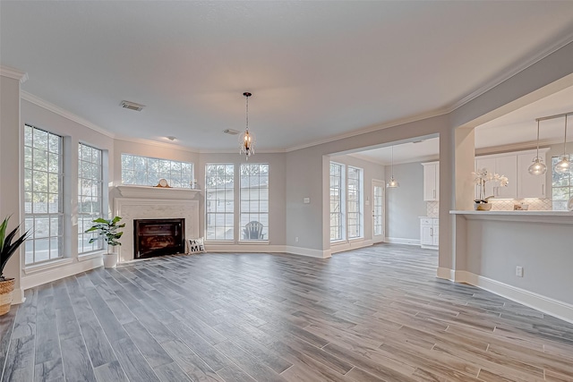 unfurnished living room with ornamental molding, a chandelier, and light wood-type flooring