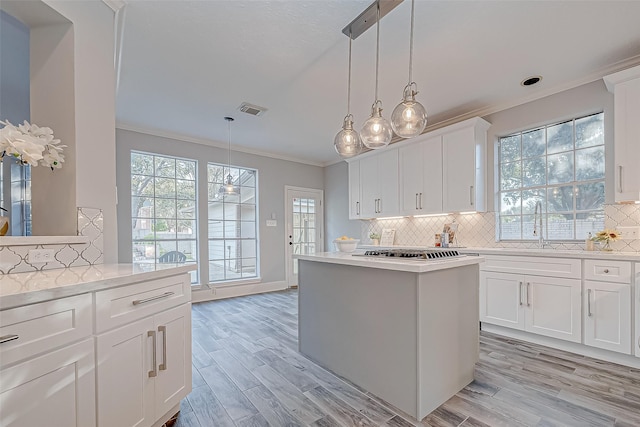 kitchen with white cabinets, light hardwood / wood-style floors, and pendant lighting