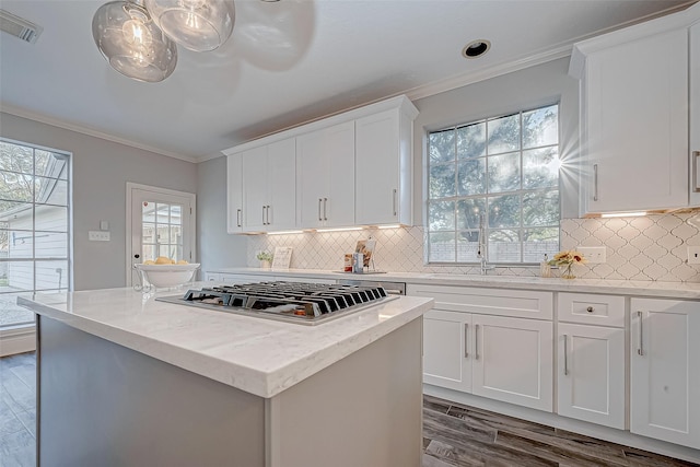 kitchen featuring white cabinetry, stainless steel gas cooktop, a kitchen island, and ornamental molding