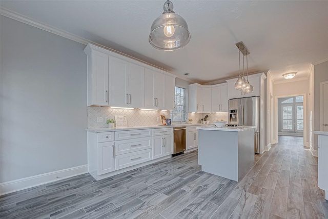 kitchen featuring stainless steel appliances, tasteful backsplash, pendant lighting, white cabinets, and a center island