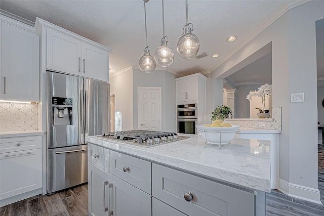 kitchen with white cabinets, decorative backsplash, appliances with stainless steel finishes, and a kitchen island