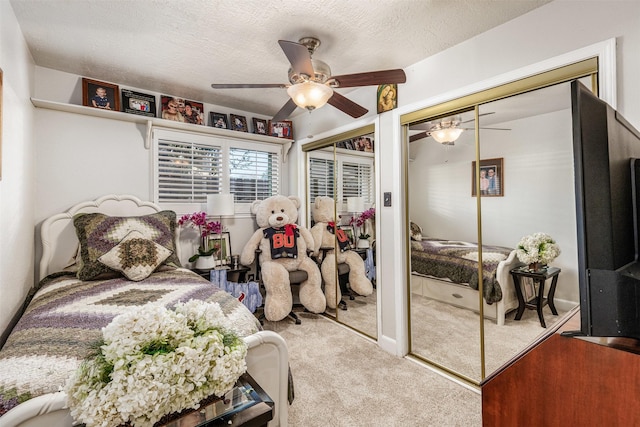 carpeted bedroom featuring multiple closets, ceiling fan, and a textured ceiling