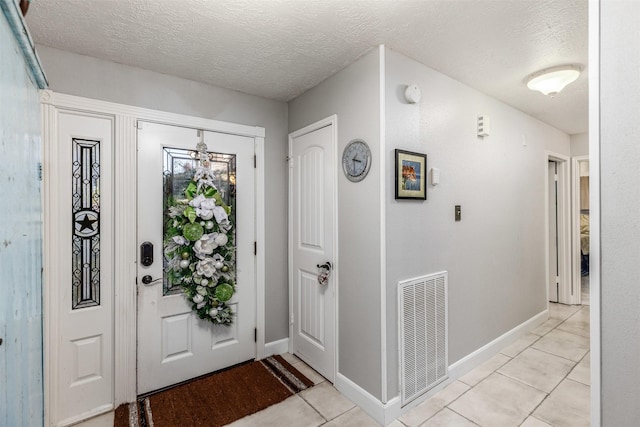 foyer entrance with light tile patterned floors and a textured ceiling