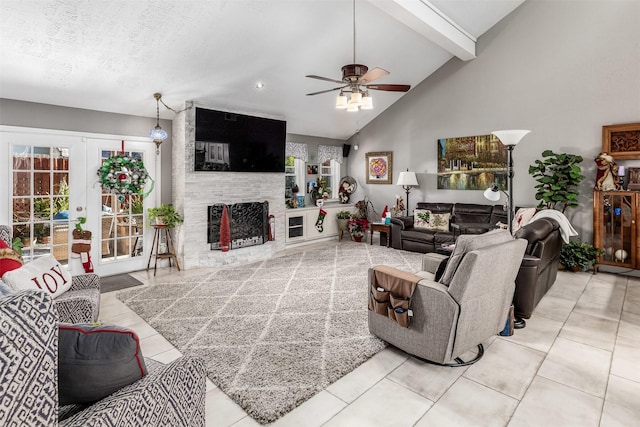 living room with beam ceiling, ceiling fan, french doors, a stone fireplace, and light tile patterned floors