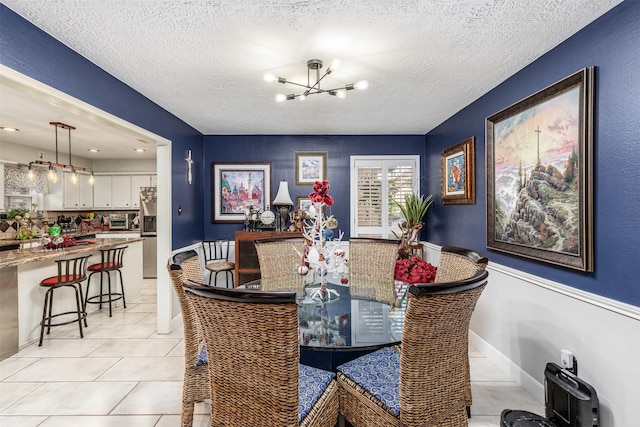 tiled dining space with a notable chandelier and a textured ceiling