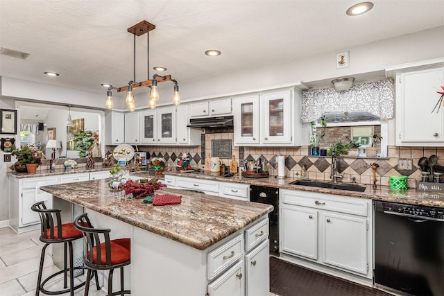 kitchen with a center island, hanging light fixtures, black dishwasher, light stone counters, and white cabinetry