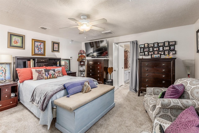 carpeted bedroom featuring ceiling fan, a textured ceiling, and ensuite bath