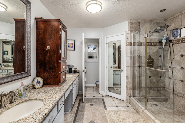 bathroom featuring toilet, vanity, a textured ceiling, and walk in shower