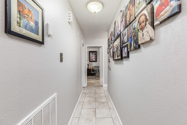 hallway featuring light tile patterned flooring and a textured ceiling