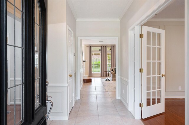 entryway with light tile patterned floors and crown molding