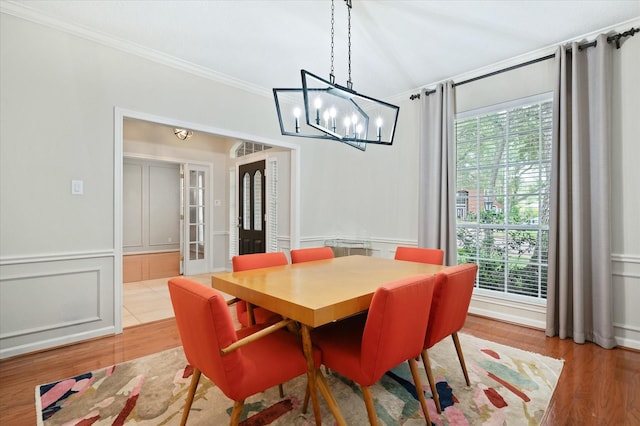 dining area with hardwood / wood-style flooring, ornamental molding, and a chandelier