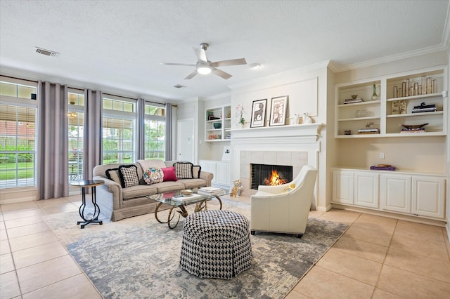 living room with a tile fireplace, light tile patterned floors, a textured ceiling, and built in shelves