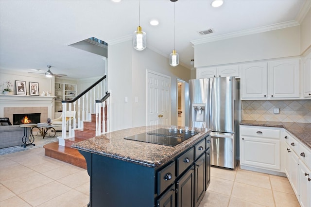 kitchen featuring white cabinets, stainless steel refrigerator with ice dispenser, black electric cooktop, and a tile fireplace