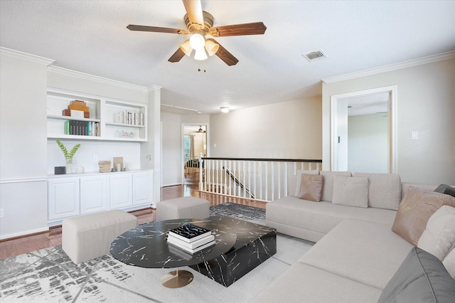 living room with ornamental molding, ceiling fan, and light wood-type flooring