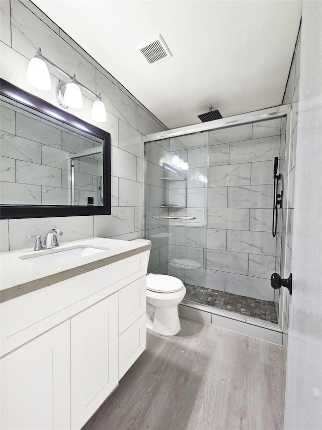 full bathroom featuring toilet, a stall shower, vanity, and visible vents