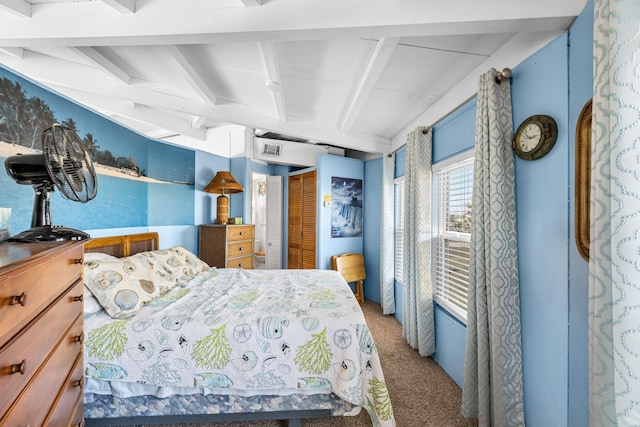 bedroom with beam ceiling, carpet floors, and a closet