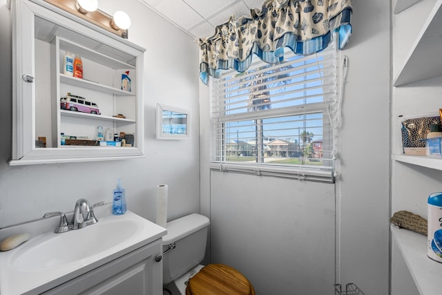 bathroom with vanity, toilet, and a drop ceiling