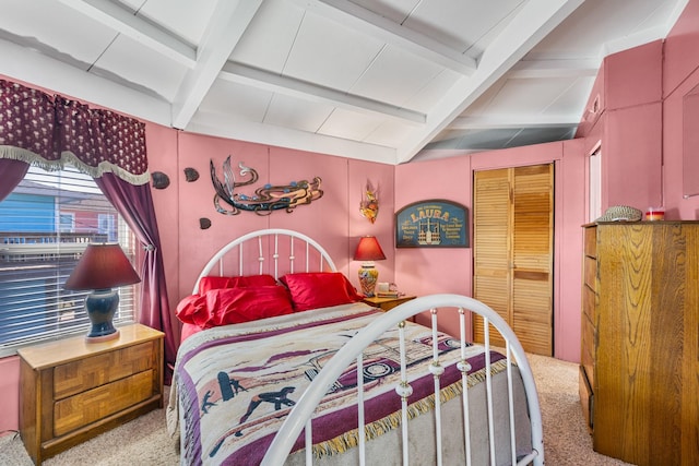 carpeted bedroom featuring a closet and beamed ceiling