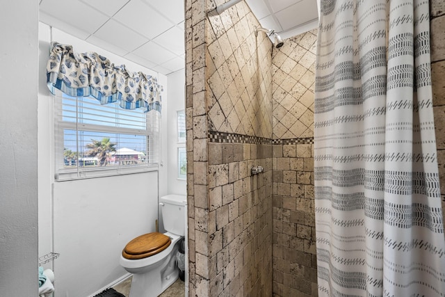 bathroom with a drop ceiling, curtained shower, and toilet