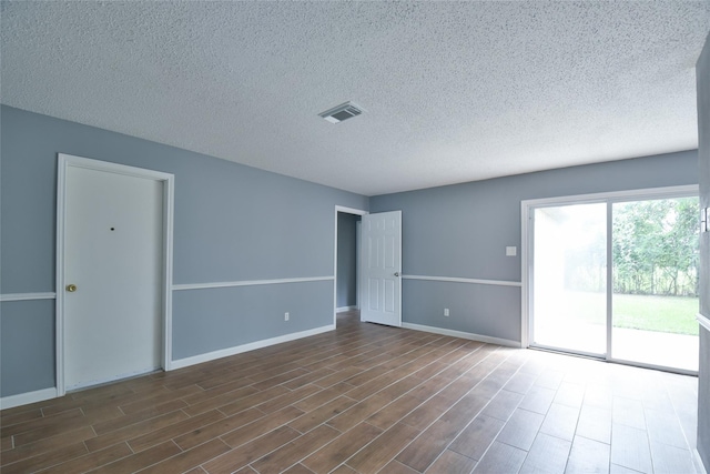 empty room featuring a textured ceiling and dark hardwood / wood-style floors