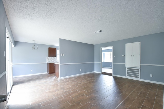 empty room featuring a chandelier, a textured ceiling, and hardwood / wood-style flooring